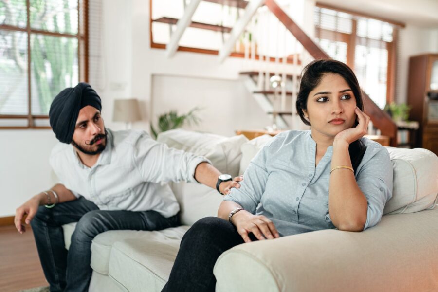 thoughtful man talking to upset woman on couch