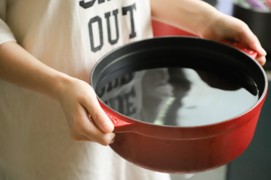 person holding red pot filled with water